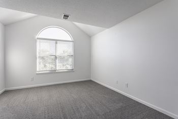 A room with a large window and carpeted floor